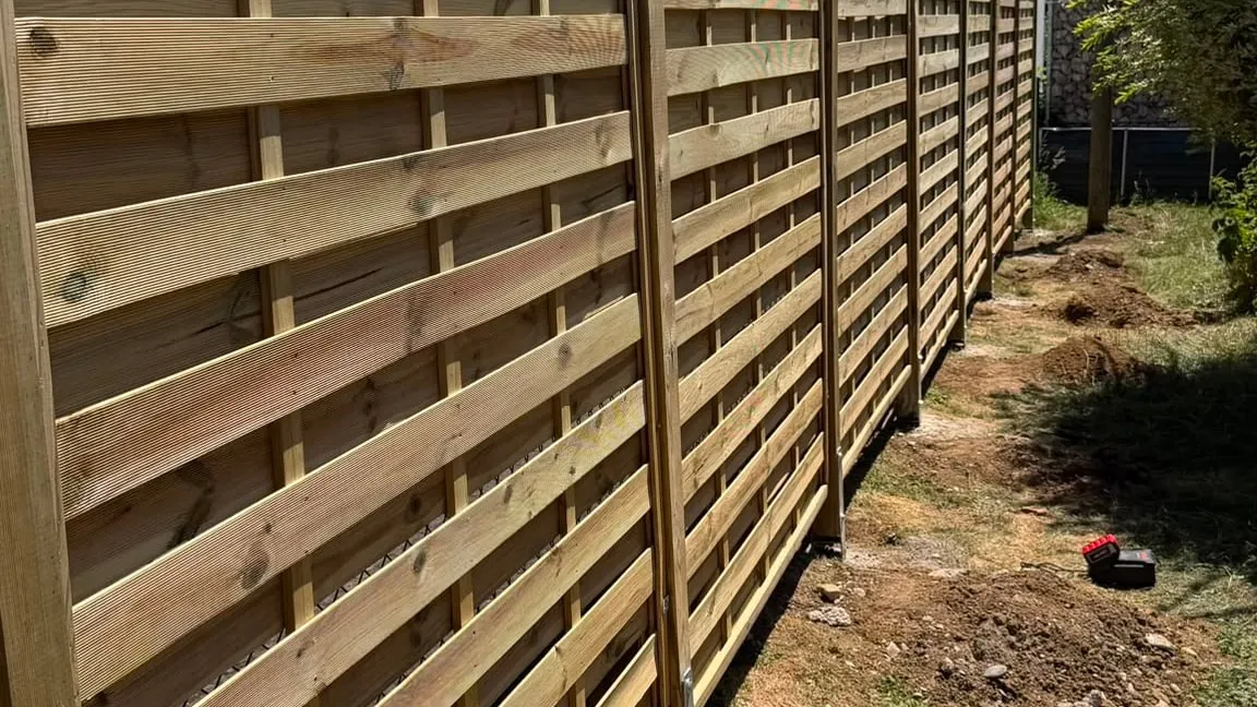 Sichtschutzzaun aus Holz entlang einer Grundstücksgrenze, frisch gesetzt