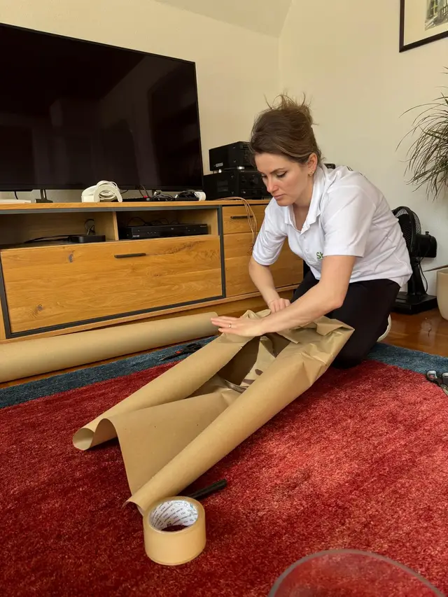 Mitarbeiterin verpackt Möbel mit Packpapier für den Umzug