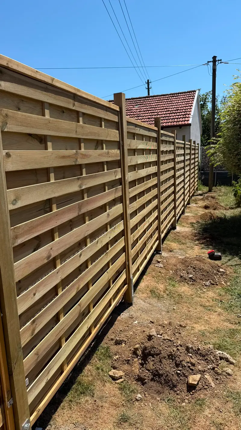Neu gesetzter Sichtschutzzaun aus Holz entlang einer Grundstücksgrenze
